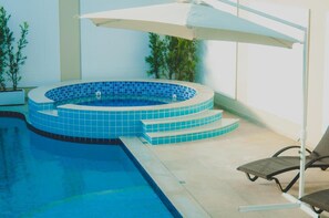 Piscina con jacuzzi, rodeada de escalones y macetas con plantas.