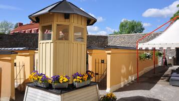 A yellow building with a black roof, a stone wall, and a red tent.