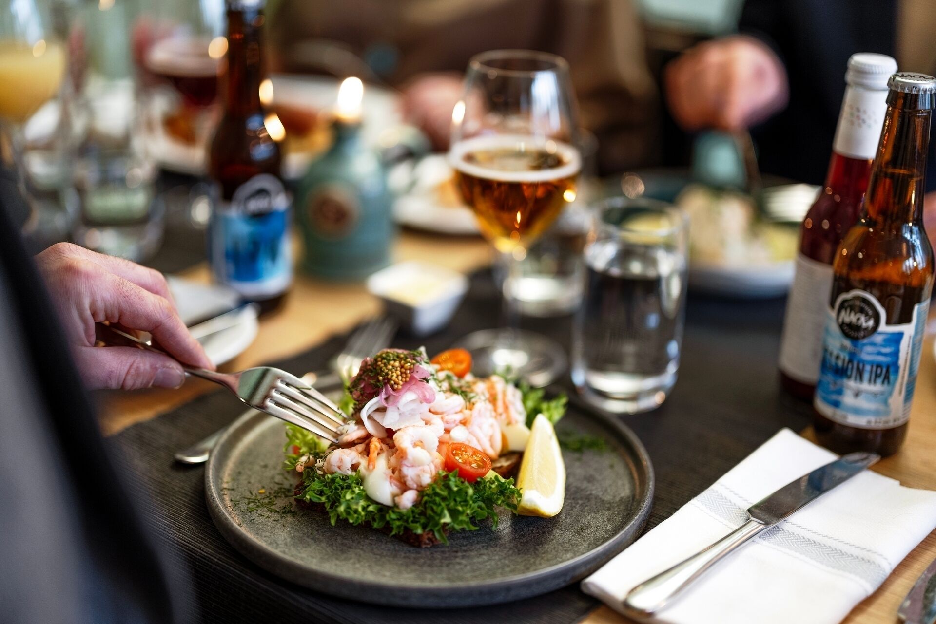 Una mesa de comedor con un plato de comida, una jarra de cerveza y botellas de cerveza.