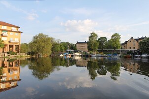 Un río tranquilo con barcos amarrados, rodeado de edificios y árboles.