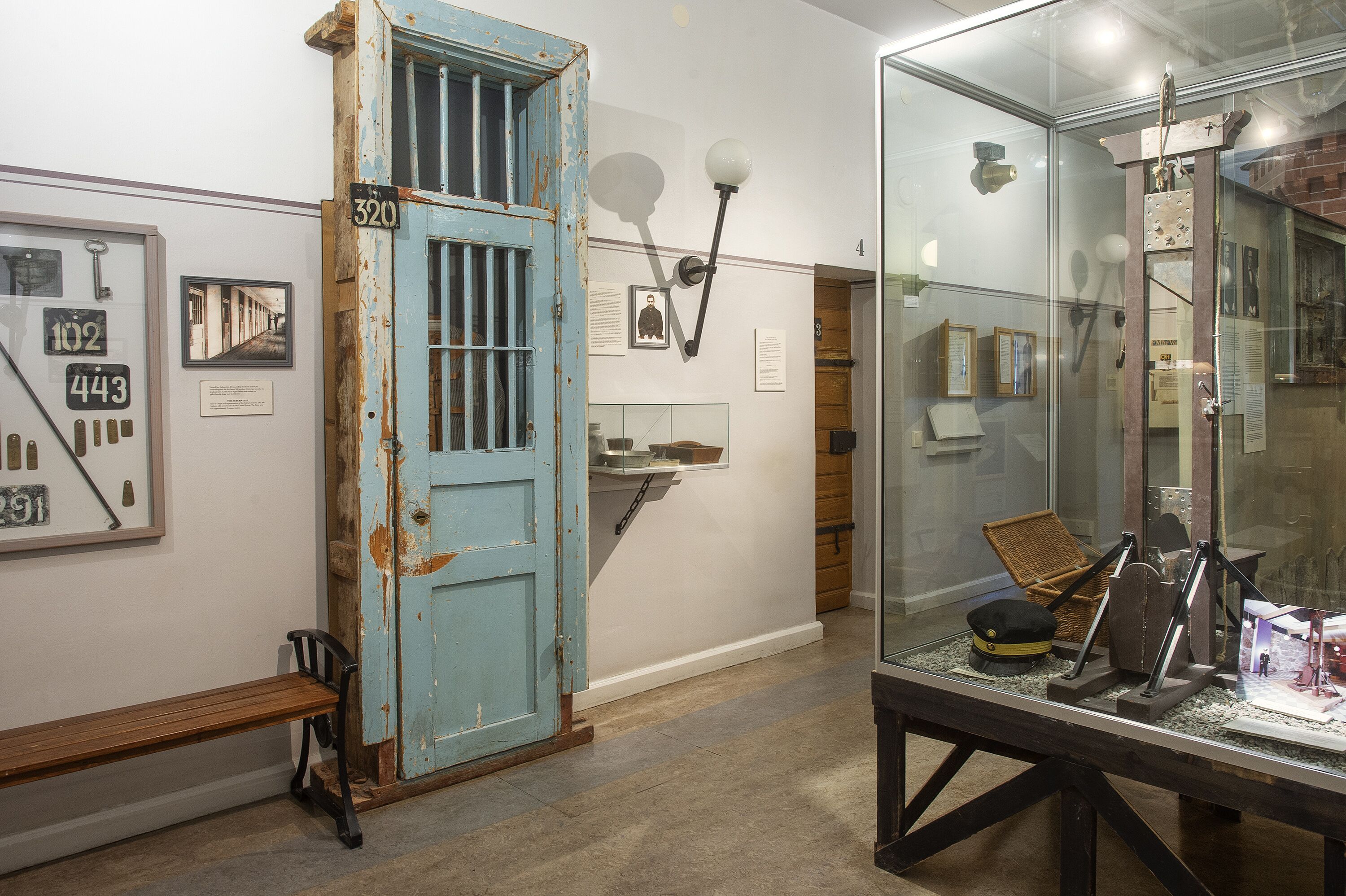 A room with a blue door, a bench, and a display case with various items.