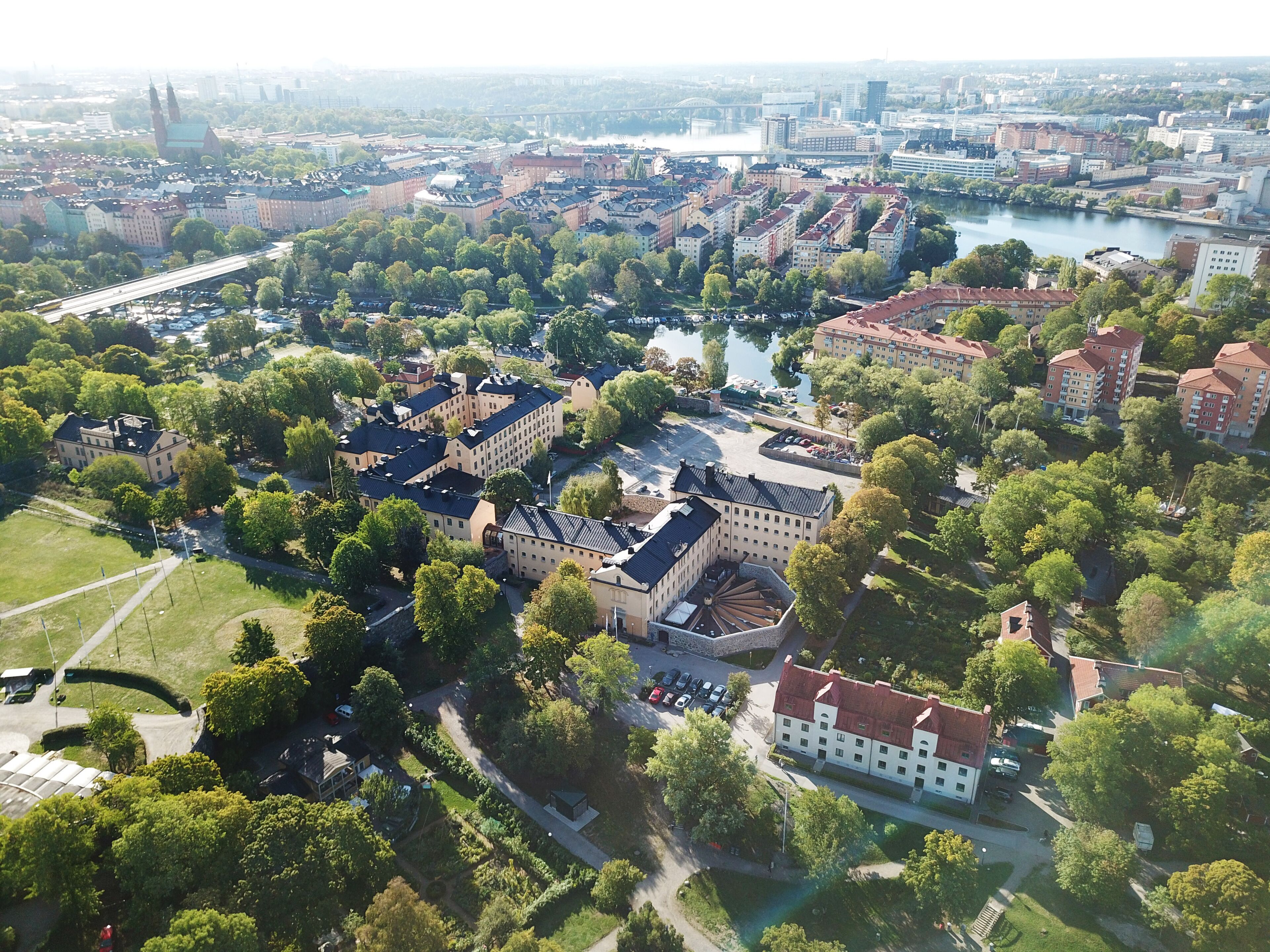 An aerial view of a cityscape with a prominent building complex featuring multiple structures, a river, and surrounding greenery.