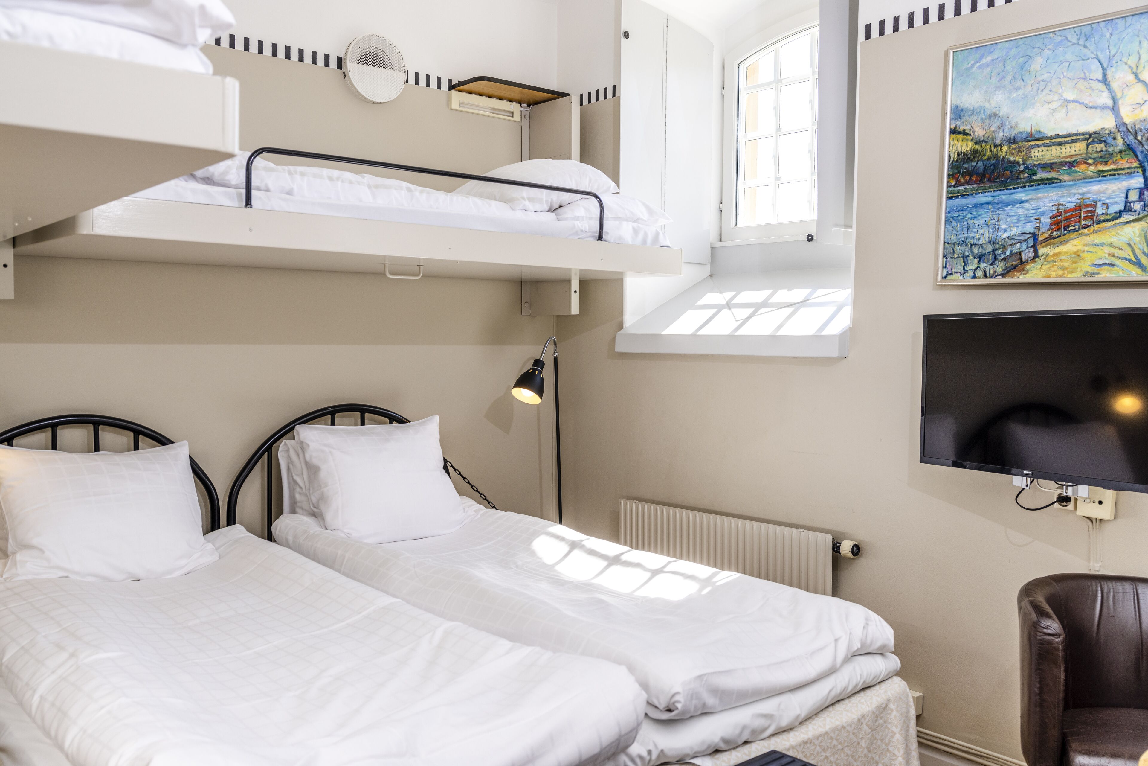 A room with two beds, a TV, and a painting on the wall.