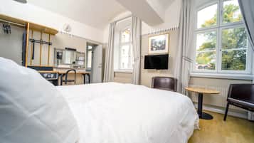 Habitación de hotel con una cama grande, un escritorio con silla, televisión y una ventana con cortinas.