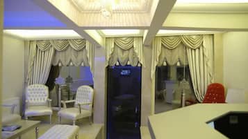 A room with a modern ceiling design, a black cabinet, and a red chair.