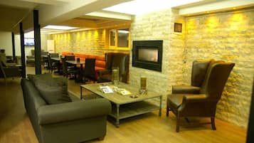 A modern lounge area with a stone wall, comfortable seating, a fireplace, and a television.
