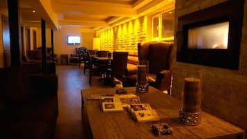 Eine gemütliche Lounge mit einem Holztisch, der verschiedene Gegenstände zeigt, einem Kamin und bequemen Sitzgelegenheiten.
