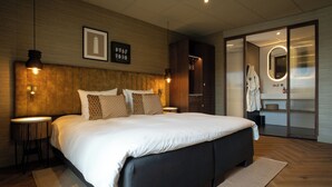 Een moderne slaapkamer met een groot bed, houten hoofdbord, nachtkastjes en een inloopkast.