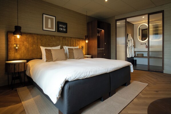 Un dormitorio moderno con una cama grande, cabecera de madera, mesitas de noche y un vestidor.