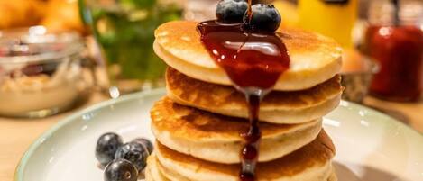 Una pila de tortitas con almíbar y arándanos en un plato.