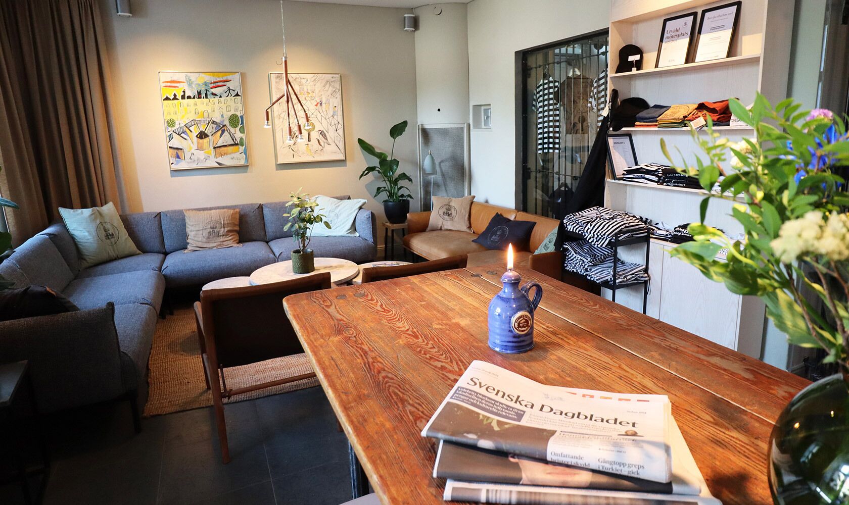 A modern living room with a grey sofa, a wooden coffee table, and a bookshelf with clothing.