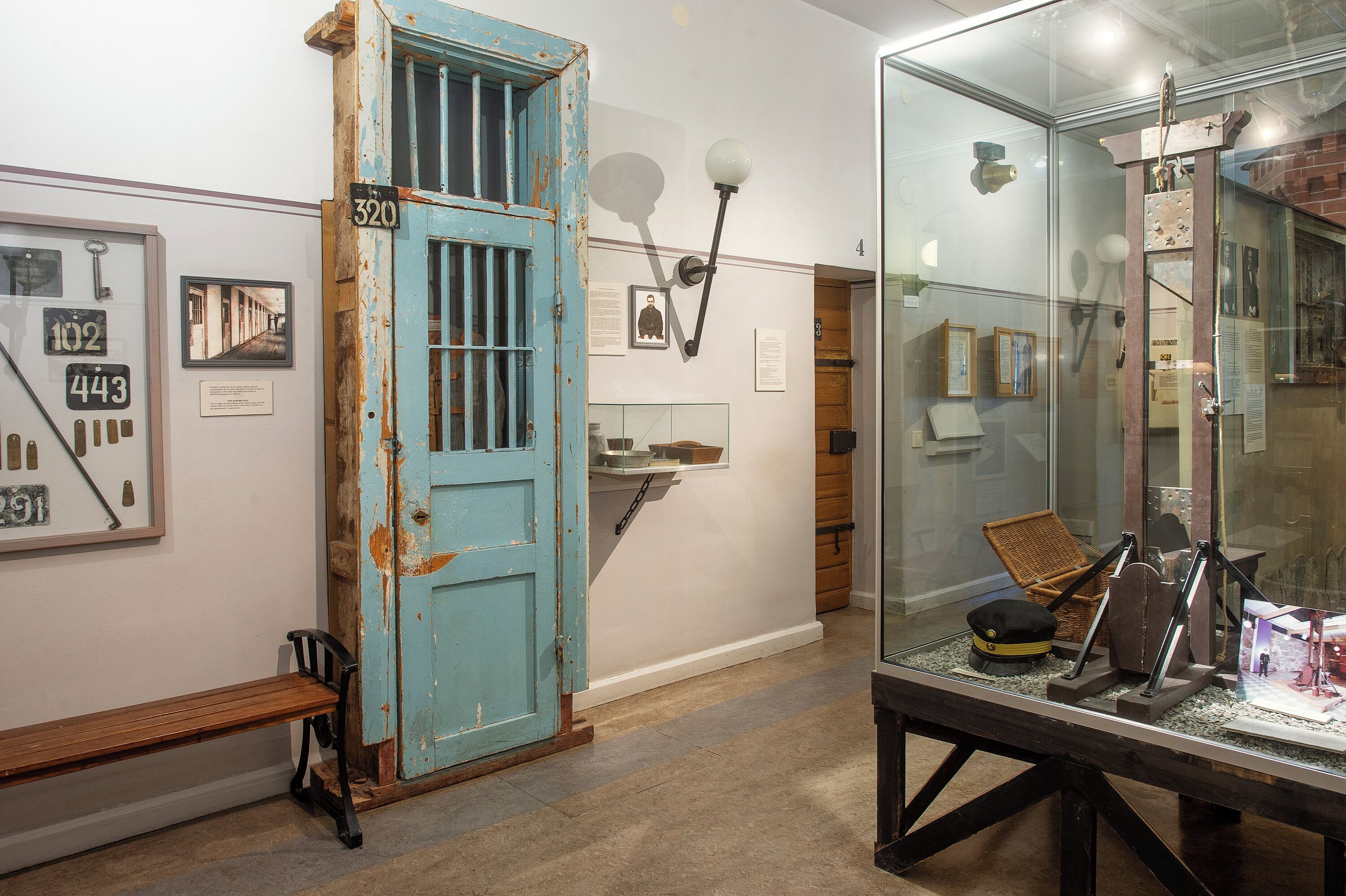 A room with a blue door, a bench, and a display case with various items.