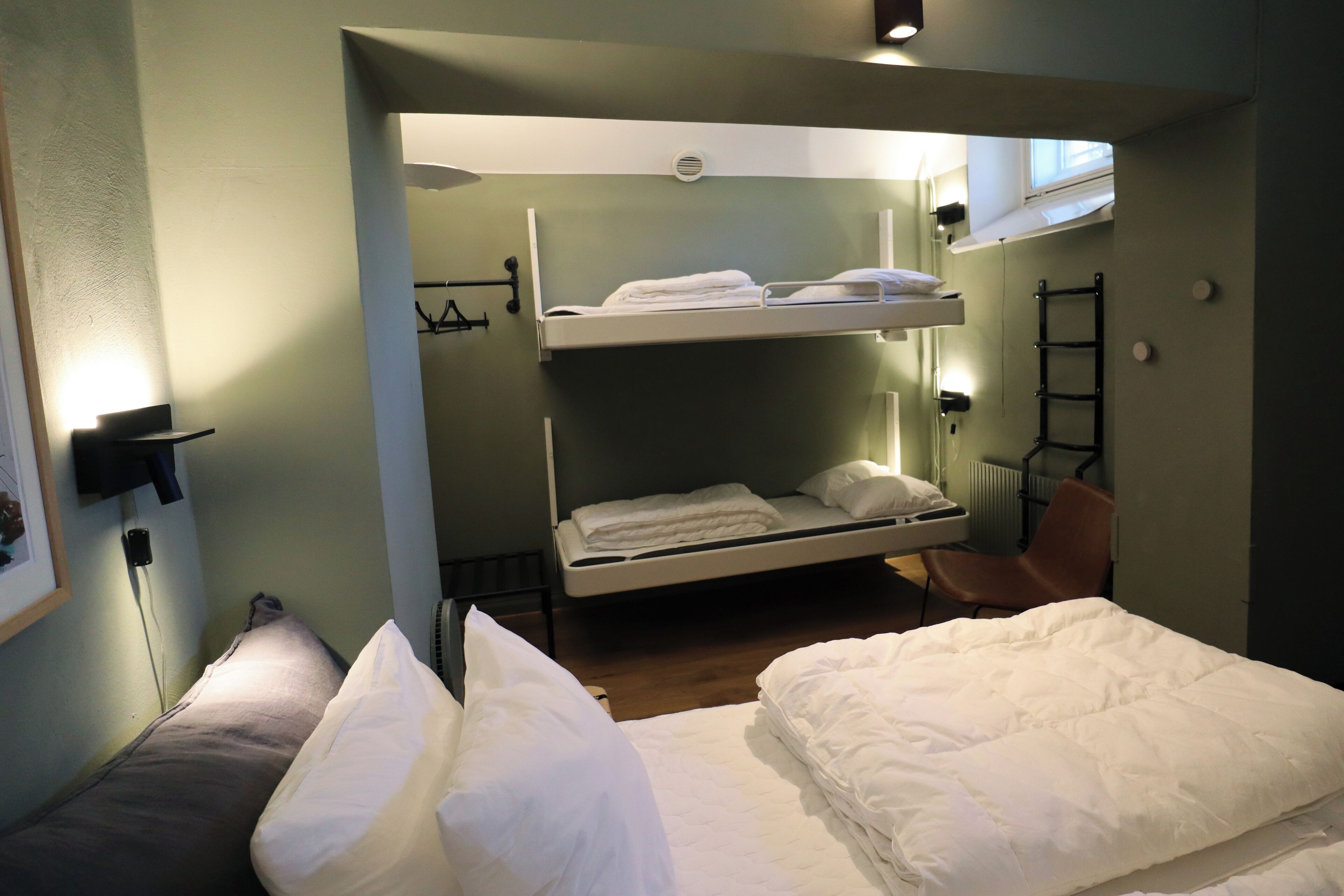 A bunk bed room with a lower bunk, a chair, and a radiator.