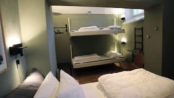 A bunk bed room with a lower bunk, a chair, and a radiator.