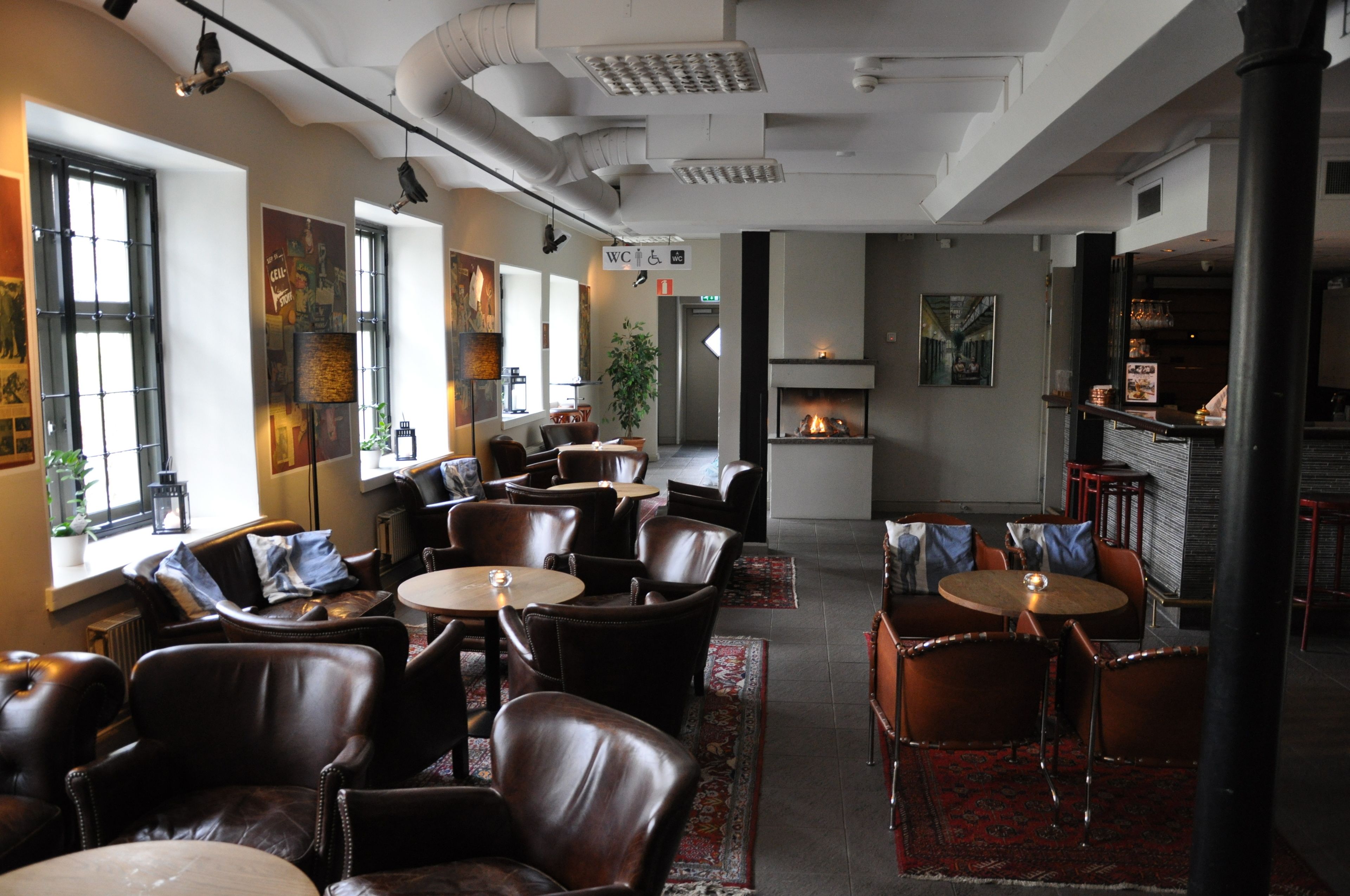 A modern interior with leather chairs and tables, a fireplace, and artwork on the walls.