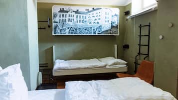 A bunk bed room with a mural of buildings on the wall, a ladder, and a chair.