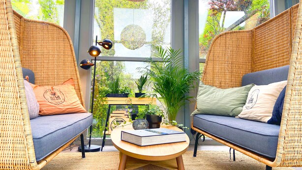 A room with two wicker sofas, a round wooden table, and a hanging spherical light fixture. - STF Långholmen Hostel (Stockholm)