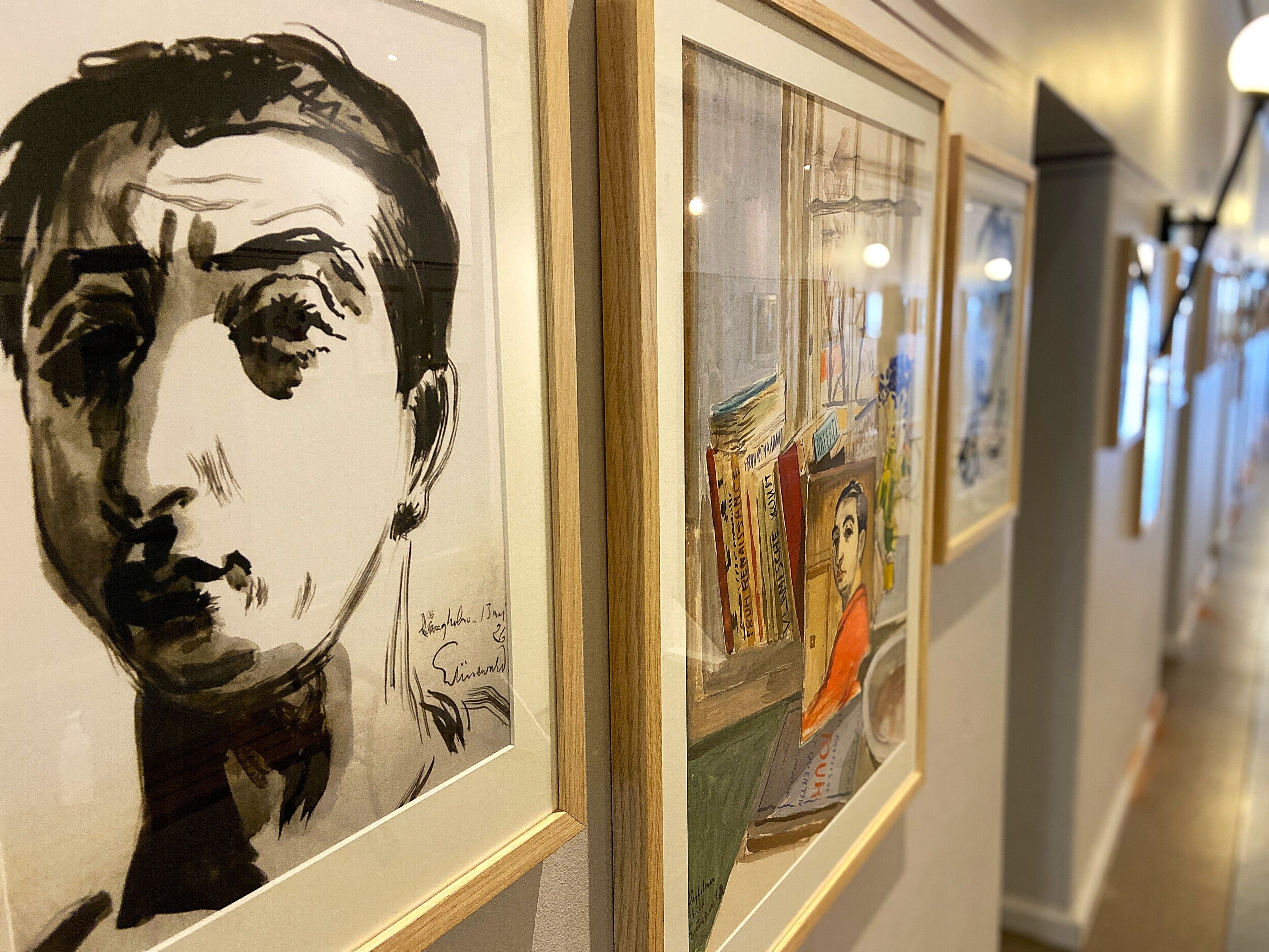 Un pasillo decorado con cuadros enmarcados, que sugiere una galería o espacio cultural.