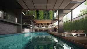 A modern indoor pool area with a clear view of the sky and greenery outside. - Happy 3 (Bangkok)