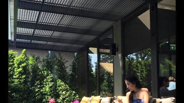 An outdoor seating area with a sofa and ottomans, a coffee table, and a flower vase. - Happy 3 (Bangkok)