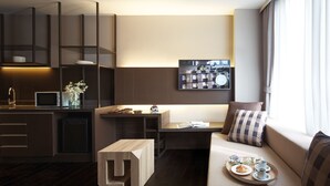 A modern, compact living space with a kitchenette, a dining area, and a seating area with a sofa and a coffee table. - Happy 3 (Bangkok)