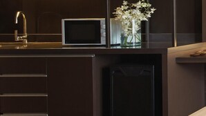 A modern kitchen with dark cabinetry, a microwave, a sink, and a vase with flowers. - Happy 3 (Bangkok)