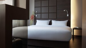 A modern hotel room with a large bed, a nightstand, a wall-mounted lamp, and a ceiling light. - Happy 3 (Bangkok)