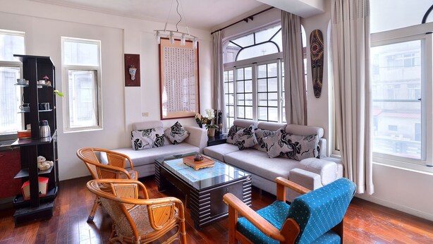 Una sala de estar con un sofá, dos sillones, una mesa de centro y una estantería.
