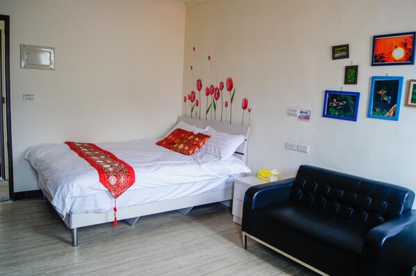 Un dormitorio con una cama, un sofá negro y obras de arte en la pared.