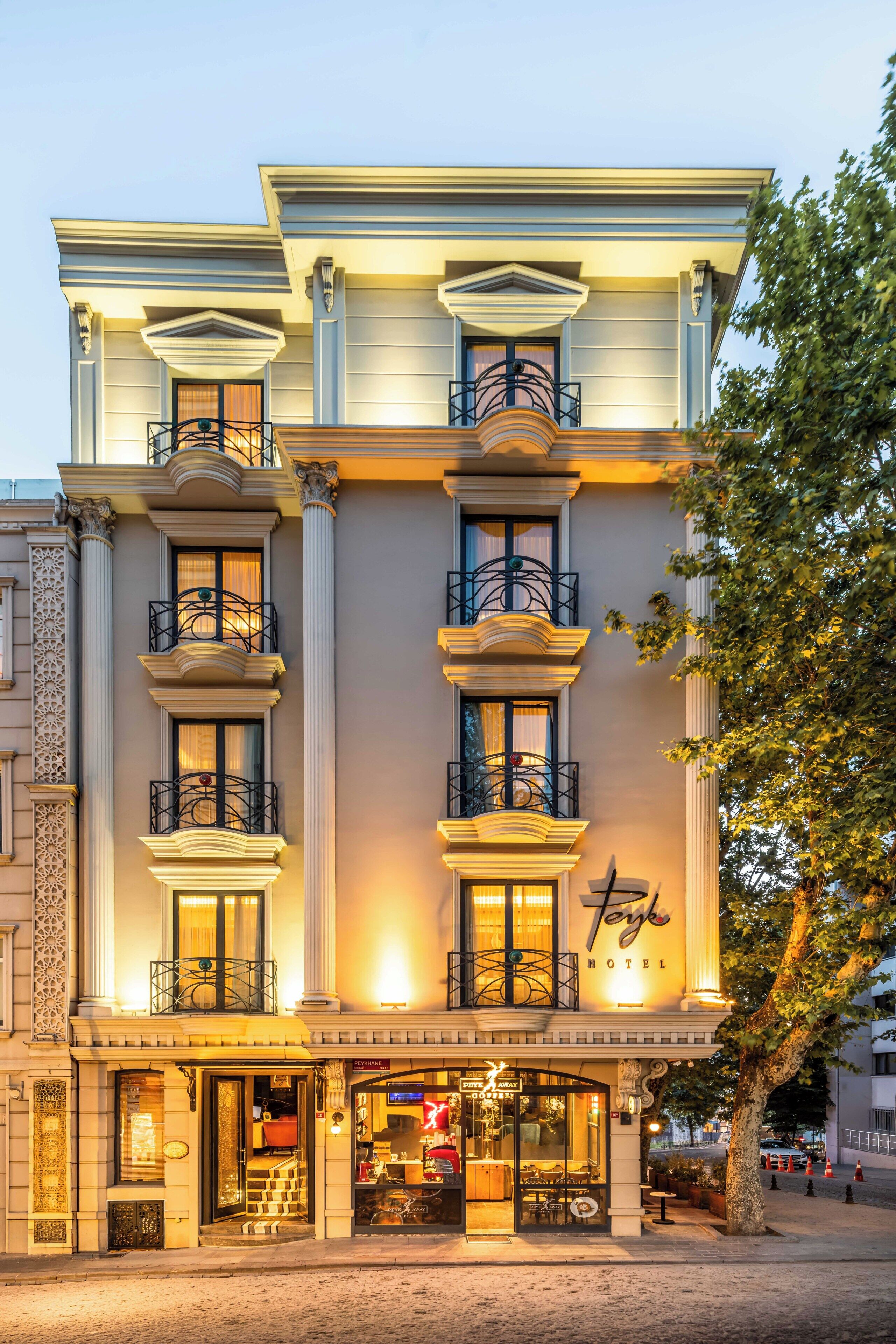 Un hôtel à la façade classique, doté de nombreux balcons et abritant un café au rez-de-chaussée.