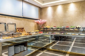 A buffet with various food items, a glass partition, and a decorative flower arrangement. - Peyk Hotel Sultanahmet (Istanbul)