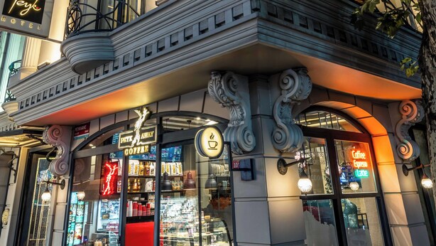 Et hotel med en klassisk facade, en café og en tydelig indgang.
