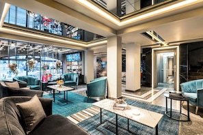 A modern hotel lobby with seating areas, a bar, and a staircase leading to an upper level. - Peyk Hotel Sultanahmet (Istanbul)