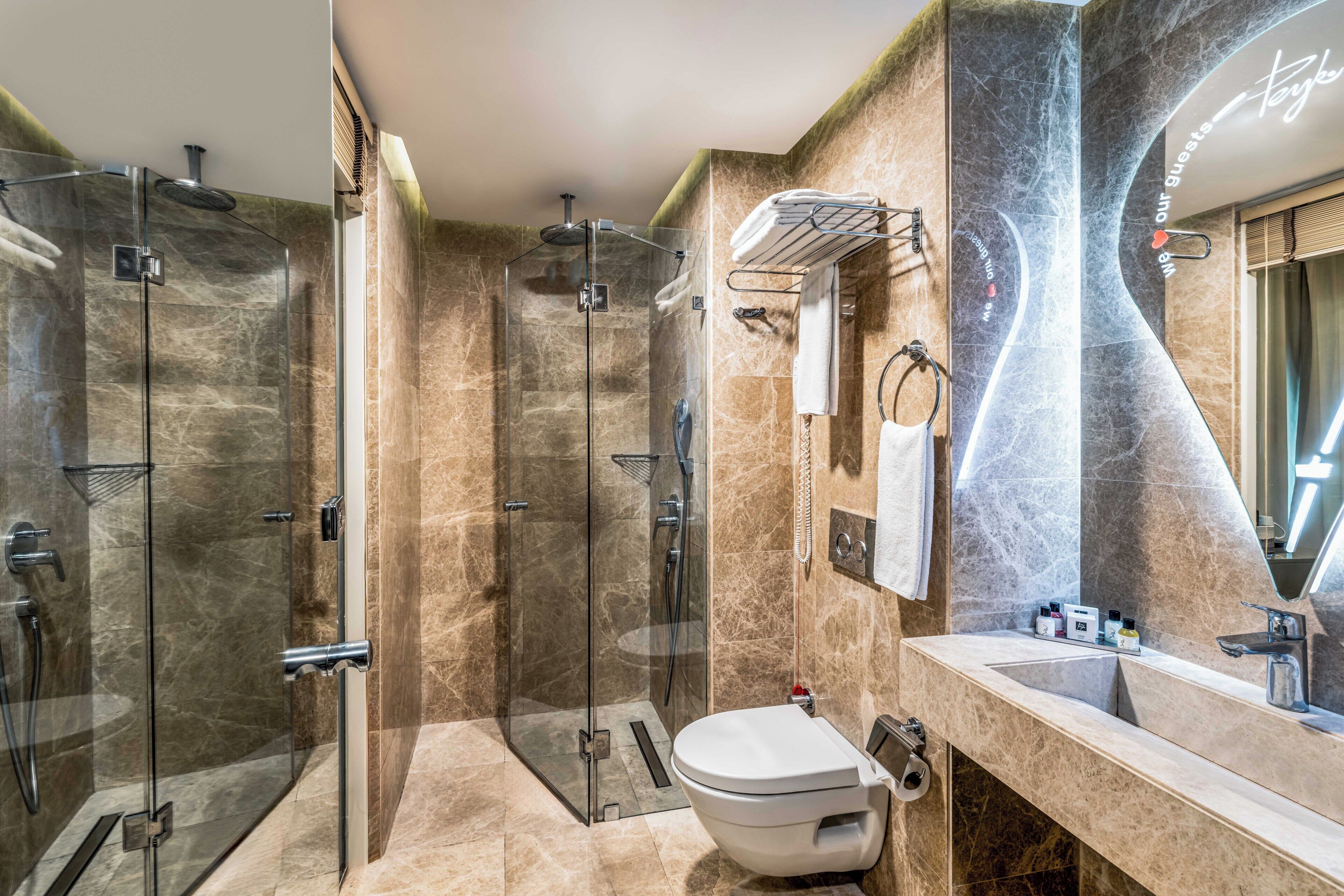 A modern bathroom with a glass-enclosed shower, a white toilet, and a vanity with a mirror.