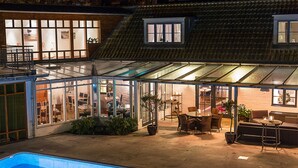 Un porche acristalado con piscina, mobiliario exterior y vistas al interior.