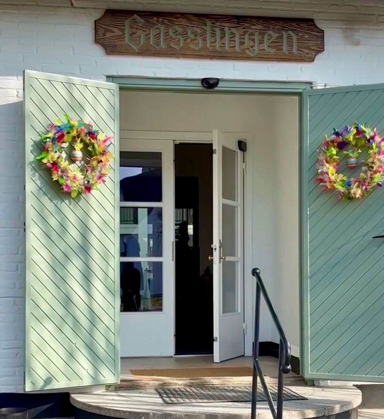 A building entrance with a sign reading "Gasthofen" and two decorative wreaths on either side.