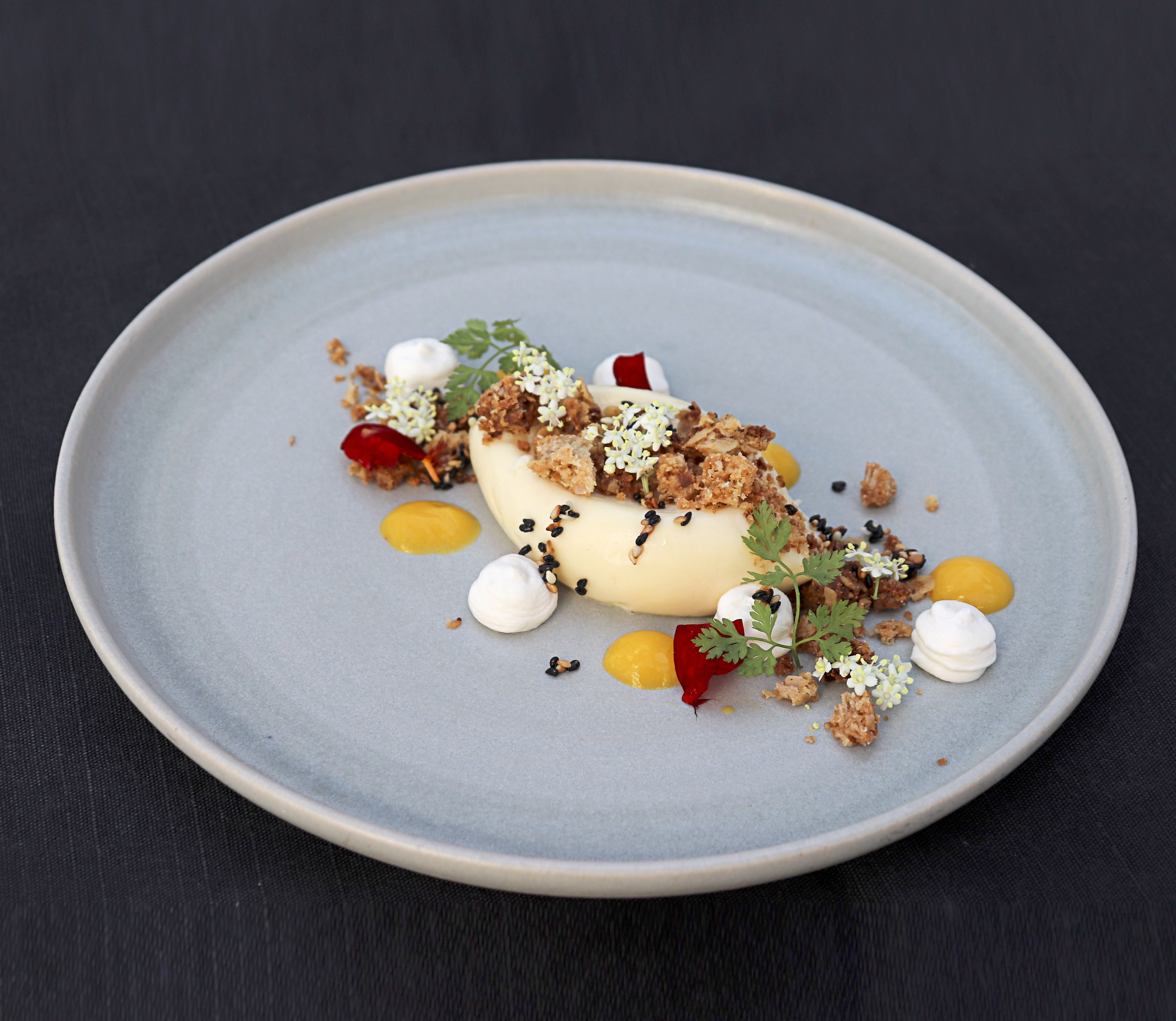 En dessert serverad på en rund tallrik, garnerad med olika sorters topping och dekor.
