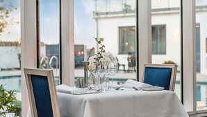 Una mesa de comedor con mantel blanco, copas de cristal transparente y un florero con flores blancas.