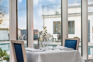 Una mesa de comedor con mantel blanco, copas de cristal transparente y un florero con flores blancas.