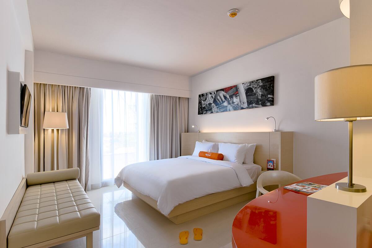 A modern hotel room with a large bed, a seating area, and a desk.