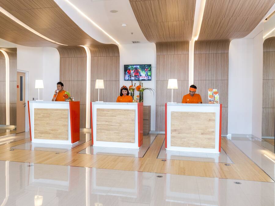 Et moderne hotelreceptionsområde med tre skranker, et stort fladskærms-tv og en slibet trægulv.
