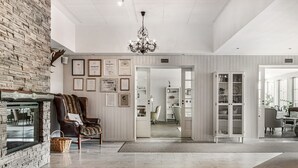 Een ruime woonkamer met een open haard, een leren fauteuil en een kroonluchter.