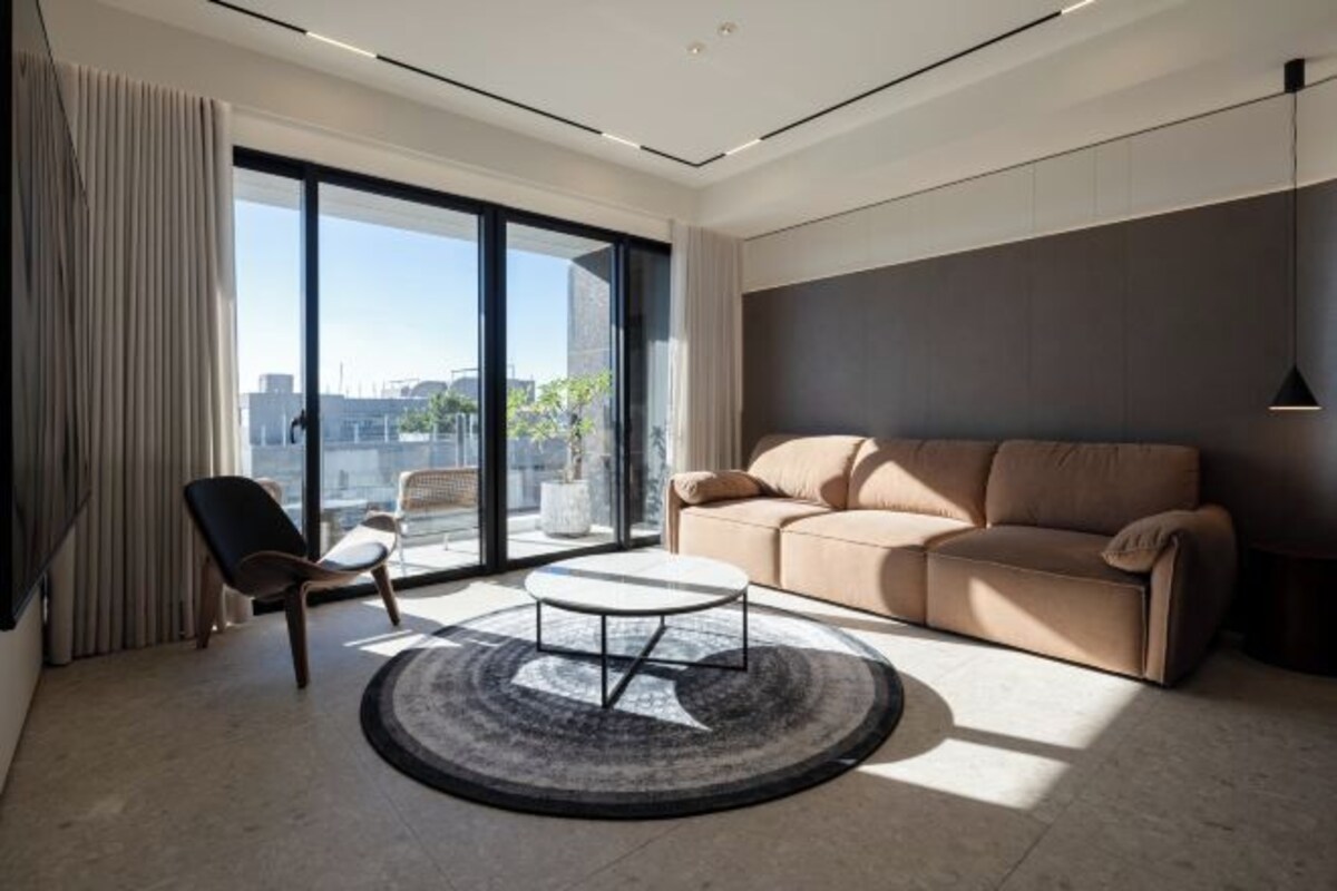 Una sala de estar moderna con un sofá color beige, una mesa de centro redonda y una butaca.