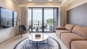 A modern living room with a large window, a sofa, a coffee table, and a chair. - Green Hotel (Magong)