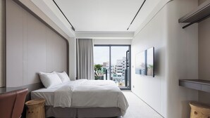 A modern hotel room with a large bed, a TV, and a view of the city. - Green Hotel (Magong)
