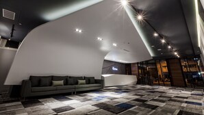 A modern lobby with a curved reception desk, a grey sofa, and a patterned carpet. - Green Hotel (Magong)