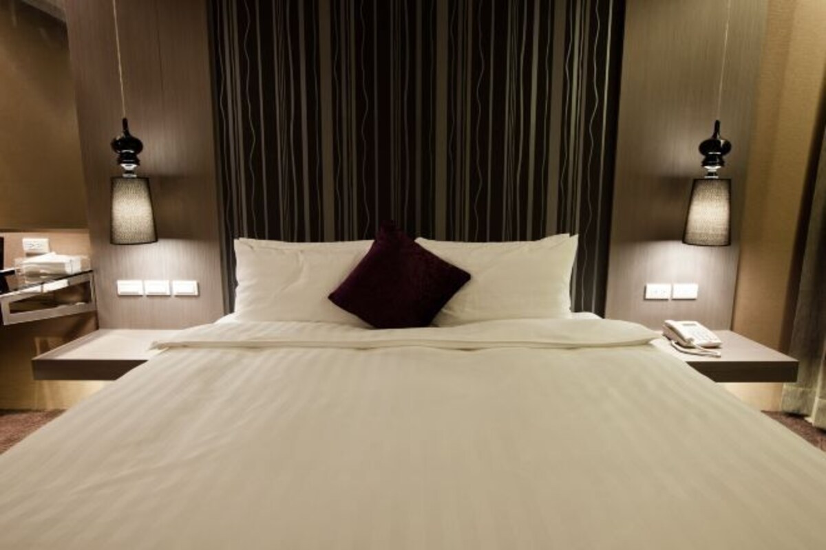 Una habitación de hotel con una cama grande, dos mesitas de noche y una lámpara de pared.