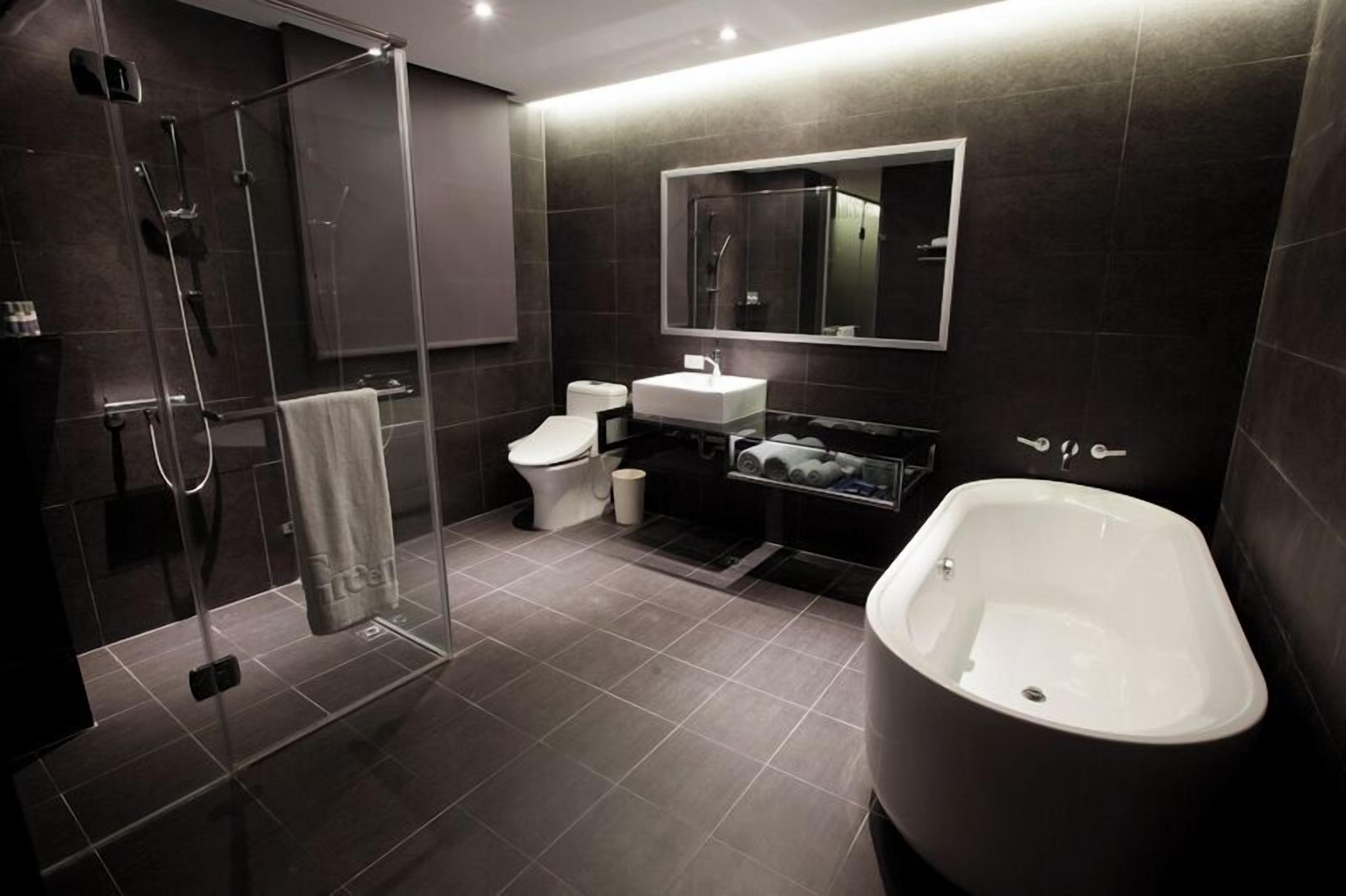 A modern bathroom with a glass-enclosed shower, a white toilet, a sink, and a freestanding bathtub.