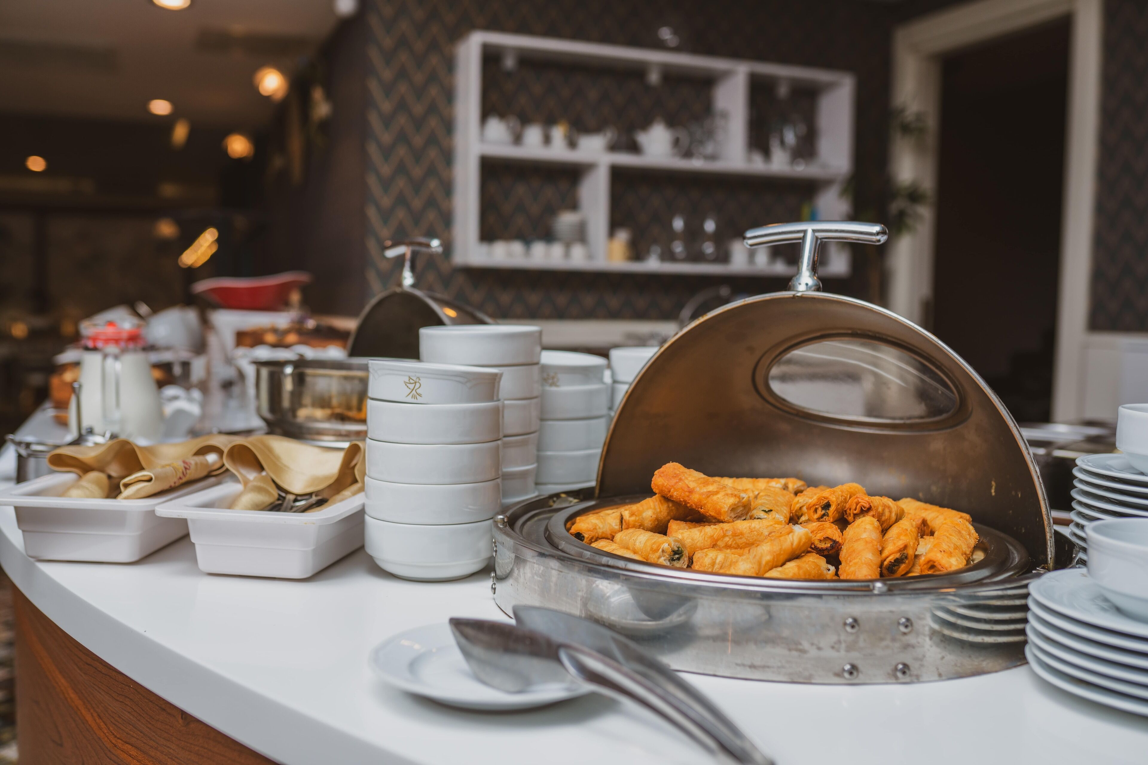 A buffet setup with various food items and serving utensils.