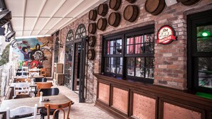 An outdoor seating area with brick walls, wooden barrels, and a sign for 'The Rosa Brasserie'. - Raymar Hotels Ankara (Ankara)